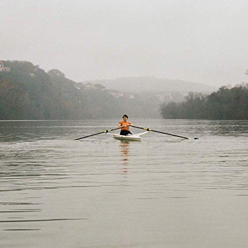 Person rowing a white boat on a misty river landscape.