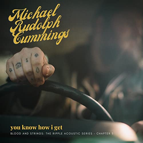 Vinyl record cover: hand holding guitar neck, gold lettering, dark background.