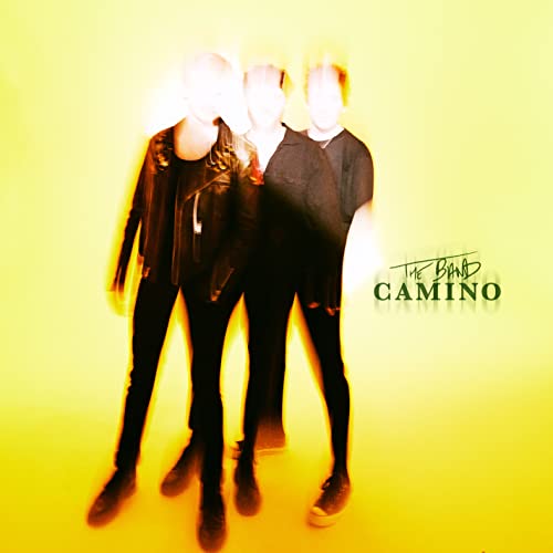 Blurred image of three people in dark clothing on a yellow background.