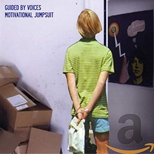 Album cover: person with boxes, artwork on wall, light blue background.