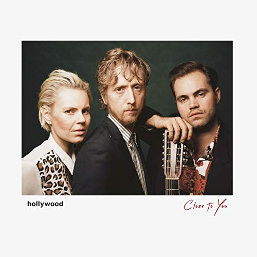 "Album cover featuring three men, one holding a guitar, against a dark background."