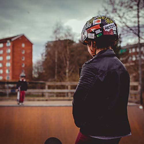 "Person wearing a helmet with stickers stands at a skate ramp."