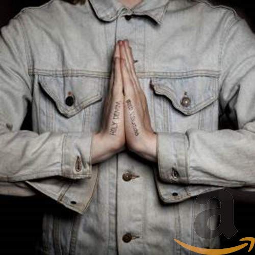 Person in denim jacket with hands pressed together in prayer.