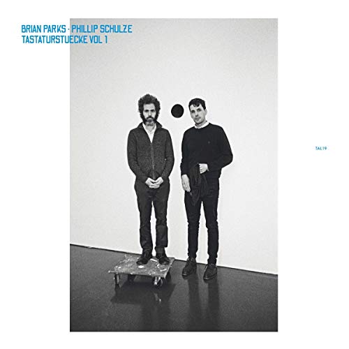 Black and white vinyl album cover featuring two men standing beside a skateboard.