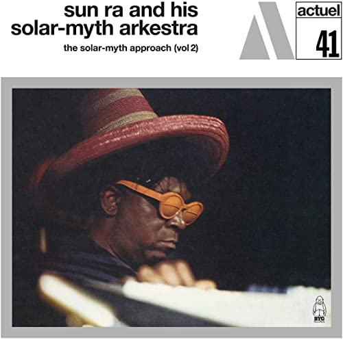 Sun Ra in red hat and orange glasses playing a keyboard.