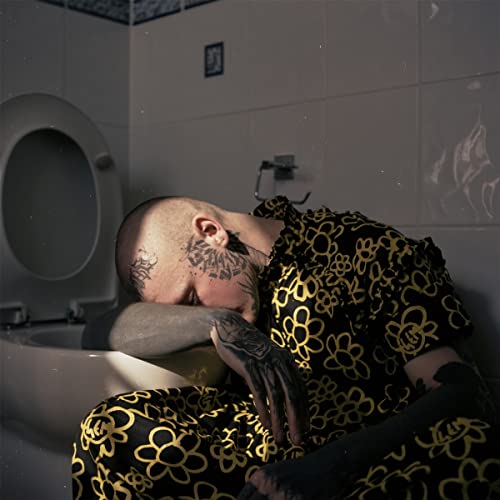 A tattooed person in a yellow-patterned outfit rests their head on a toilet bowl.