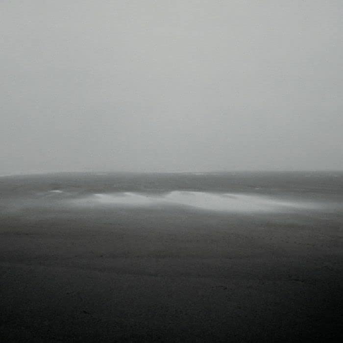 Black and white seascape with blurred waves and a hazy horizon.