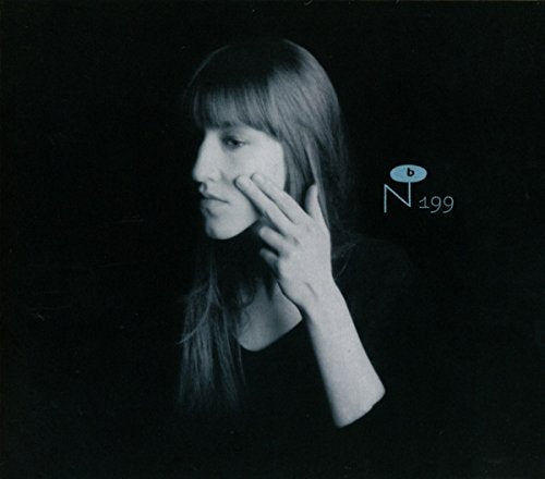 A woman with long hair touches her cheek in a black and white portrait.