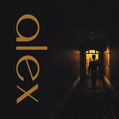 VinylLC-shaped gold text "alex" beside a person walking down a dark hotel hallway.