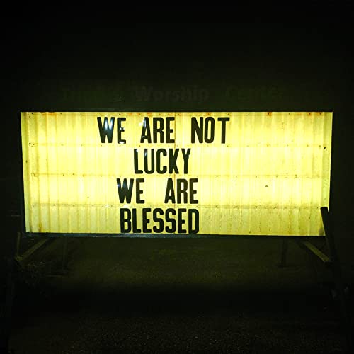 Yellow illuminated sign reading "WE ARE NOT LUCKY WE ARE BLESSED".