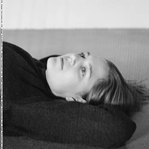 Black and white portrait of a young woman lying down, eyes open.