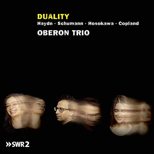 "CD cover with blurred images of three musicians against a black background."