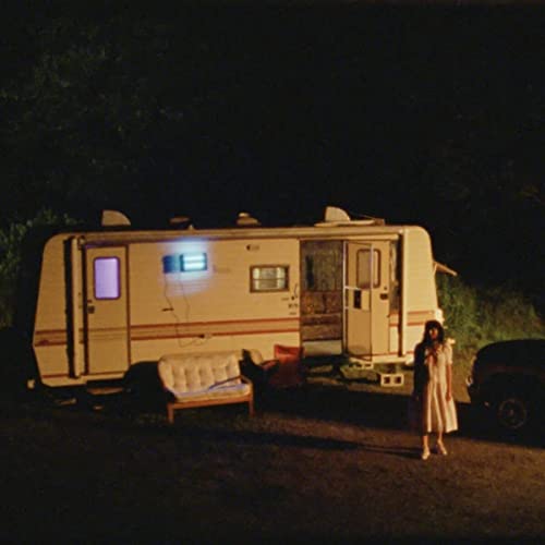 Vintage RV parked at night with a person standing nearby.
