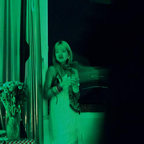 Green-toned photo of a woman in a white dress, holding flowers.