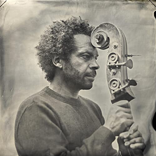 Black and white portrait of a man holding a complex mechanical device.