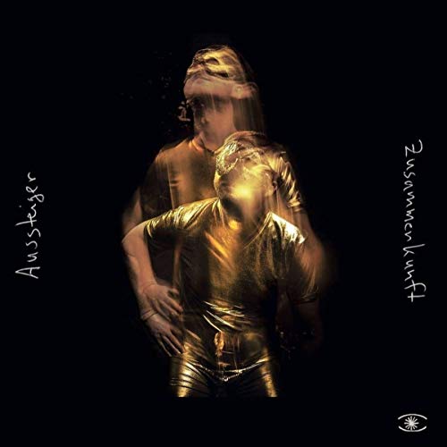 A vinyl album cover featuring two blurred, golden figures against a black background.