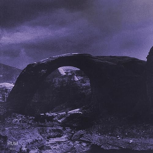 Dark, grainy album cover featuring a natural rock archway against a cloudy sky.