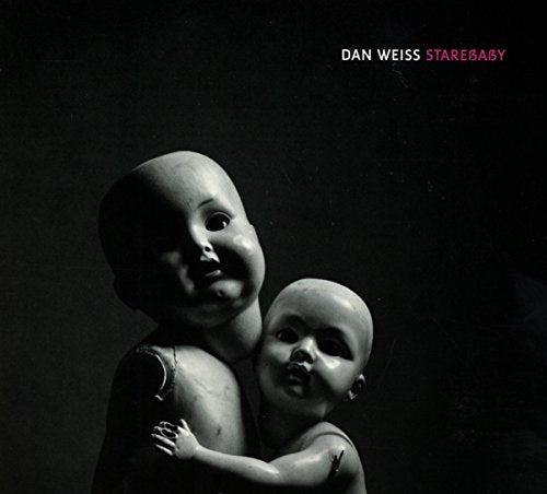 "Album cover featuring two porcelain dolls against a dark background, with artist's name."