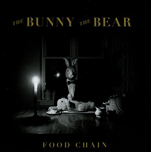 "Black and white album cover with rabbit puppet and tea setting on a table."