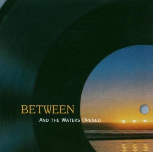 Vinyl record with a sunset scene and text "Between - And The Waters Opened".
