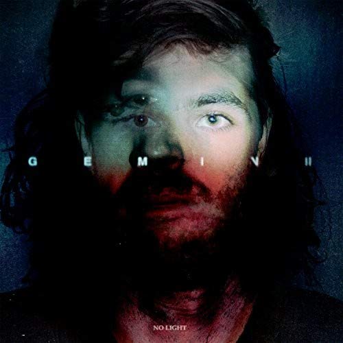 The alt text for the image is: "Man with long hair and beard, dark background, 'Gemini' across his face."