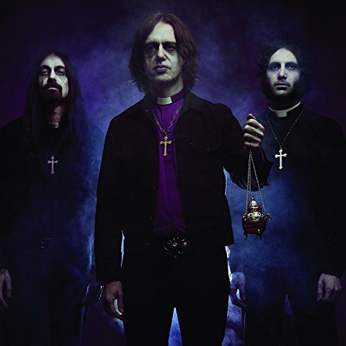 Three men in dark clothing with crosses, holding a lantern.