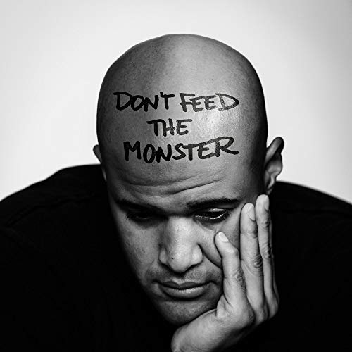 Bald man with "Don't Feed the Monster" written on his forehead in black.