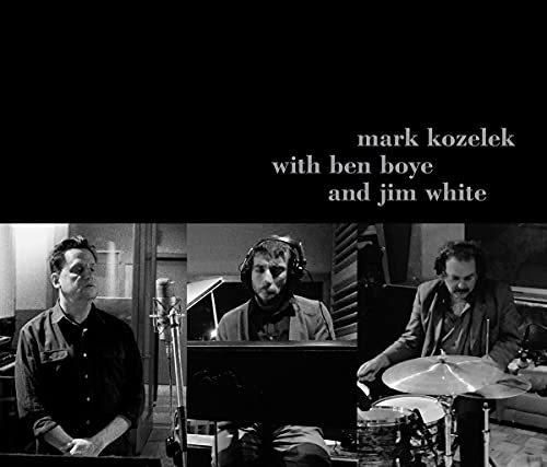 Black and white photo of three musicians in a recording studio.