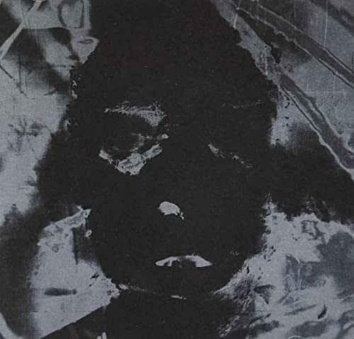 A black and white abstract image on a CD cover, with dark, distorted face-like features.