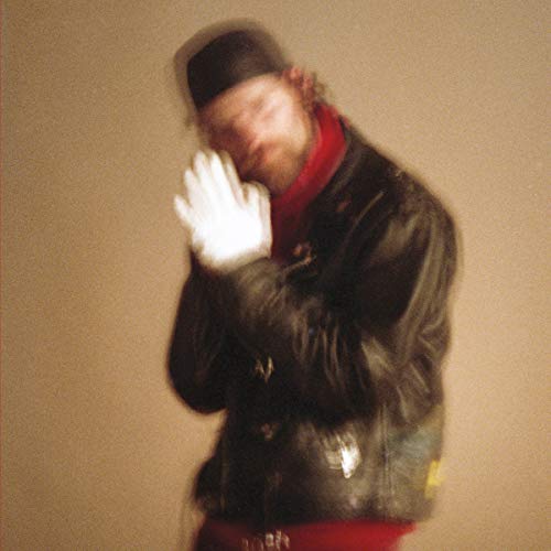 A man in a black jacket and red scarf covers his face.