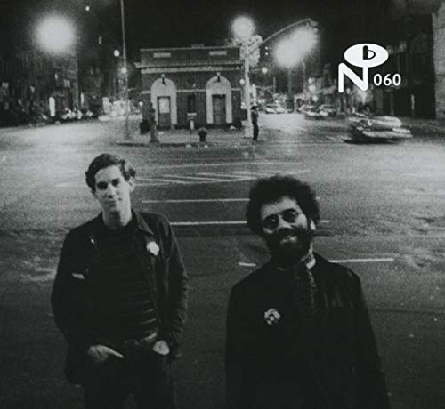 Black and white photo of two men standing in a city street at night.