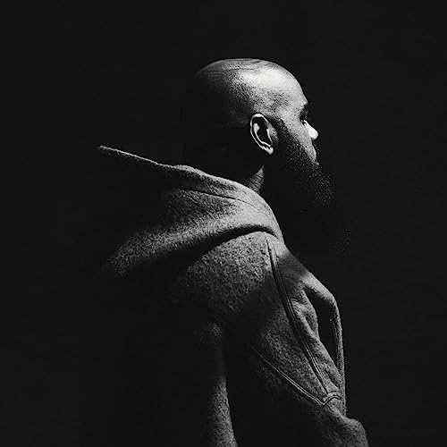 Black and white portrait of Stalley in a hooded jacket, profile view.