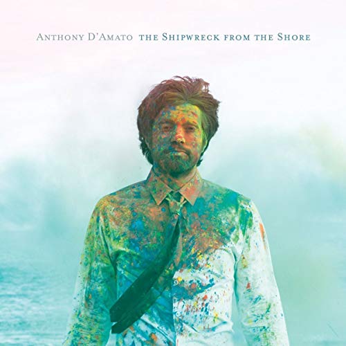 CD cover: Man covered in colorful paint against a blurred ocean.