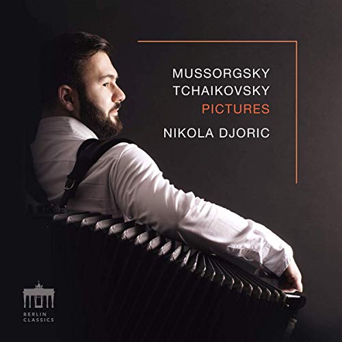 Man with dark hair and beard holds accordion, looking over shoulder, on dark background.