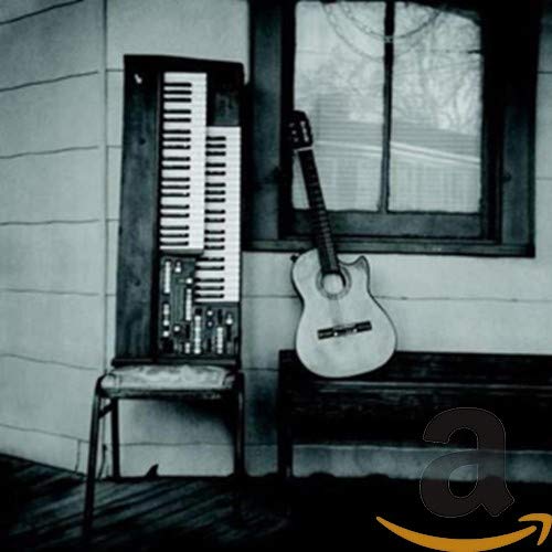 Accordion and acoustic guitar leaning against a weathered wooden building.