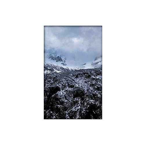 Snowy mountains and rocky terrain under a cloudy, grey sky.