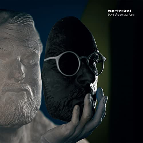 Album cover with a dark, mask-like face and blurred man in background.