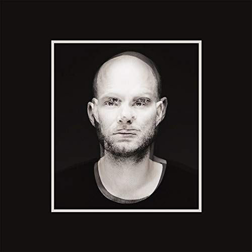 Black and white portrait of a man with a shaved head and beard.