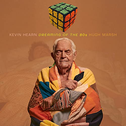 Album cover featuring an elderly man wrapped in a colorful patchwork blanket.