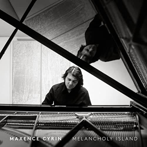 Black and white photo of Maxence Cyrin reflected in a grand piano lid.