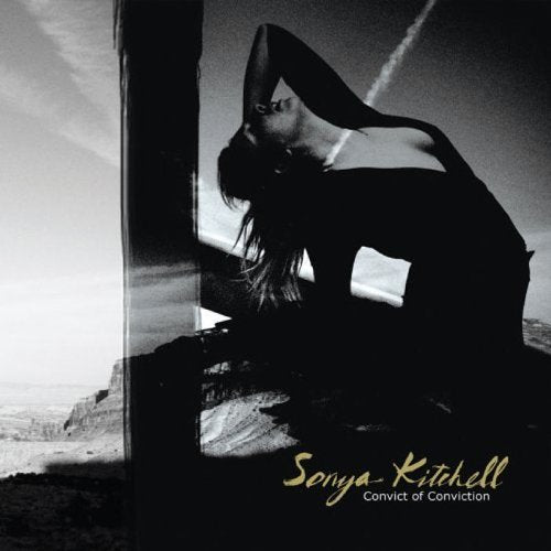 "Album cover featuring a black-and-white photo of a woman crouching, with artist and album name."