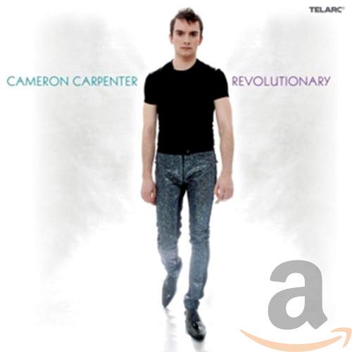 Cameron Carpenter stands against a white background wearing a black shirt and patterned pants.