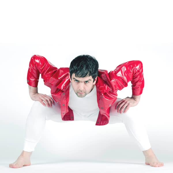 Man in red vinyl suit crouching on white background.