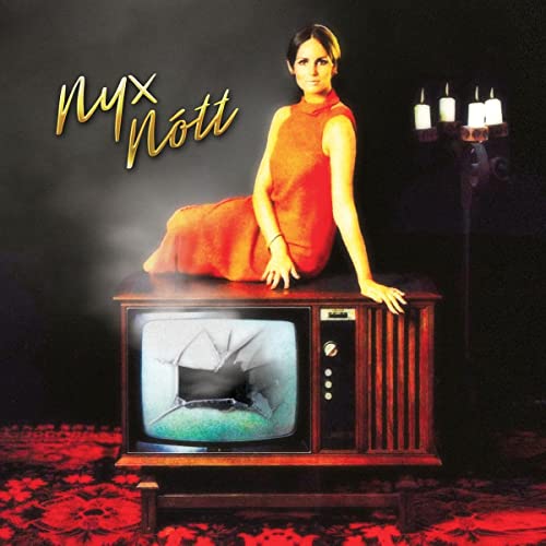 Album cover: woman in red dress seated on vintage TV, candles.
