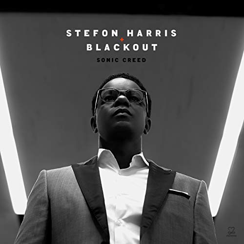 "Black and white album cover featuring a man in a suit and sunglasses."