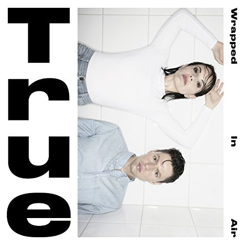 CD cover with two people lying on a tiled floor and large text.