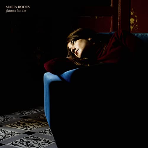 Album cover: woman reclining on a blue sofa in a dark room.