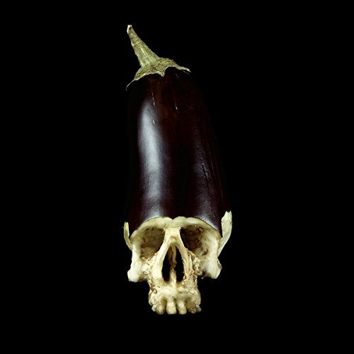 Human skull with an eggplant on top against a black background.