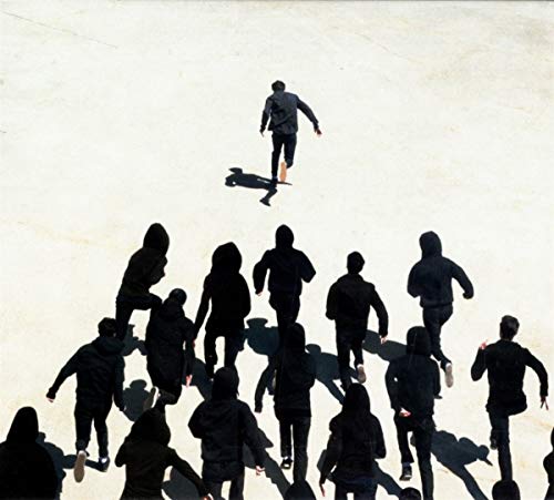 A group of people in dark hooded sweatshirts chasing a man on a light surface.