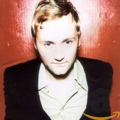 Close-up portrait of a man with short hair against a red background.